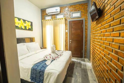 a bedroom with a bed and a brick wall at The Backyard House in Tabanan