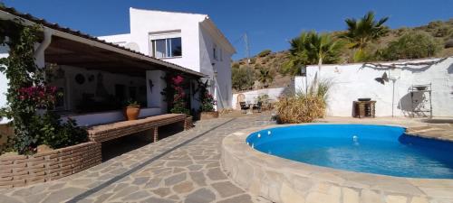 a villa with a swimming pool in front of a house at Casa Ceratonia in Alora