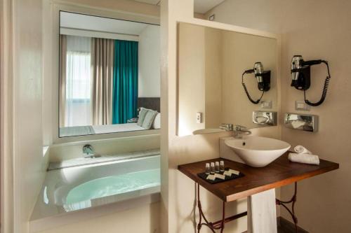 a bathroom with a tub and a sink and a mirror at Phi Hotel Milano in Baranzate