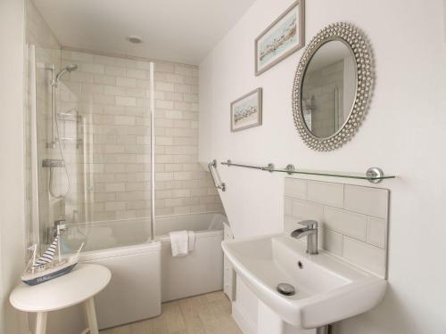 a white bathroom with a sink and a mirror at Little Gull Cottage in Weymouth