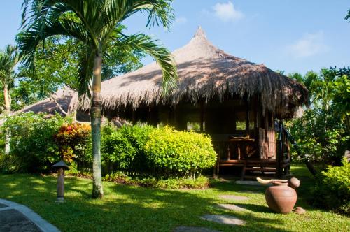 a hut with a straw roof and a palm tree at Hijo Resorts Davao in Tagum