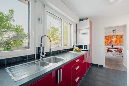 a kitchen with red cabinets and a sink at Veeve - Visual Exultation in Boulogne-Billancourt