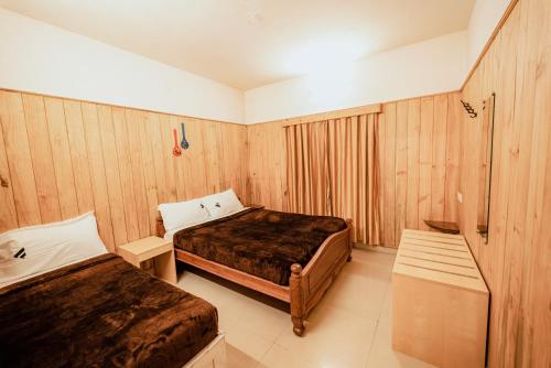 a hotel room with two beds and wooden walls at Vivera Highlands in Kodaikānāl