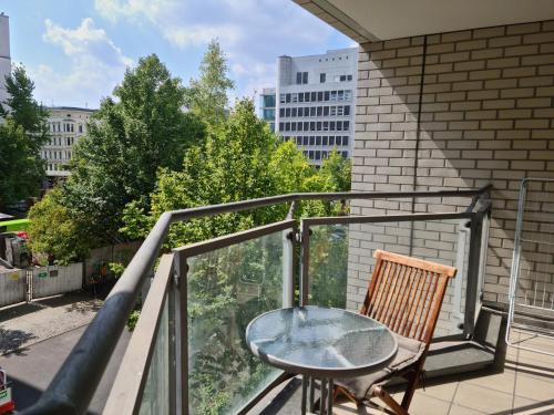 a glass table and a chair on a balcony at TopDomizil Apartments Checkpoint Plaza in Berlin