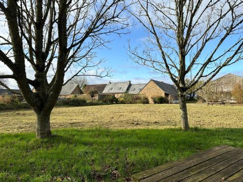 two trees in a field with houses in the background at Le Grand Ker - Gîte de Charme in Plougasnou