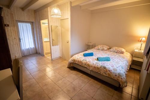 a bedroom with a bed with blue pillows on it at Le Grand Ker - Gîte de Charme in Plougasnou