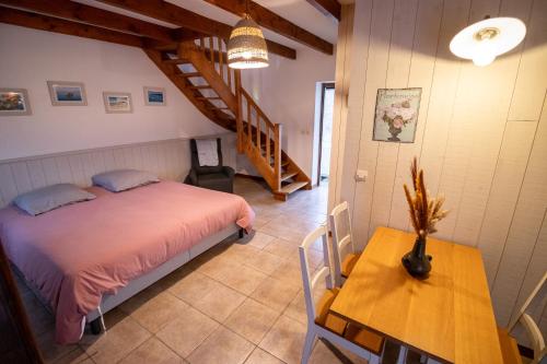 ein Schlafzimmer mit einem Bett, einem Tisch und einer Treppe in der Unterkunft Le Grand Ker - Gîte de Charme in Plougasnou