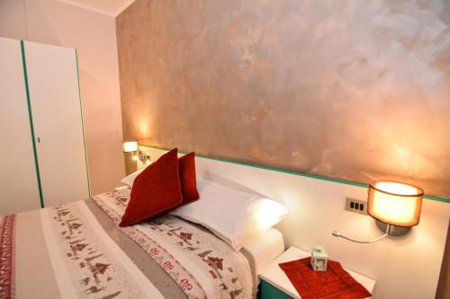a small bedroom with a bed with red pillows at Hotel Cima d'Oro in Ledro