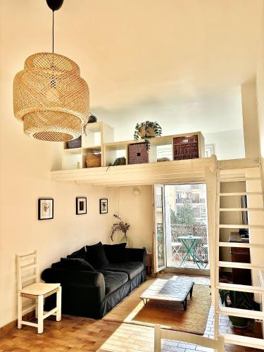 a living room with a black couch and a chandelier at Appartement cosy au cœur de Sète in Sète