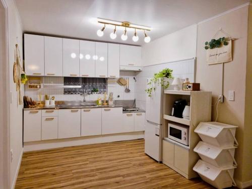 a large white kitchen with white cabinets and wooden floors at Jamsil Heaven in Seoul
