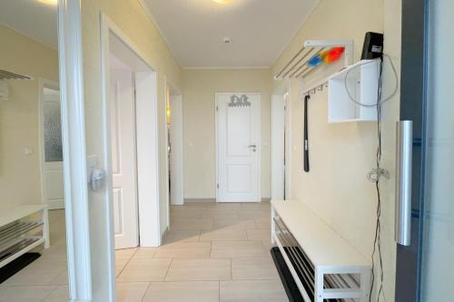 a hallway with a white door and a white bench at Strandstrasse 21 Ferienwohnung Möwennest in Kölpinsee