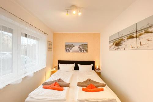 a bedroom with a bed with orange pillows on it at Strandstrasse 21 Ferienwohnung Möwennest in Kölpinsee