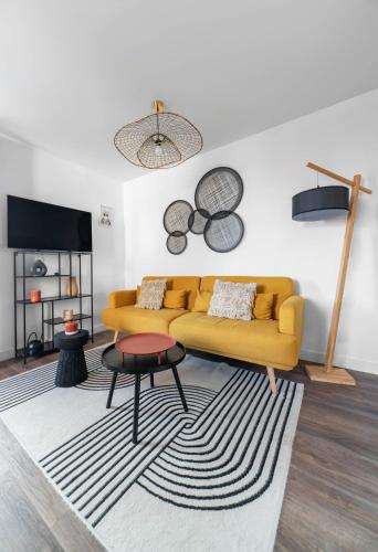 a living room with a yellow couch and a table at Résidence Léon Blum - Appartements design - Parking in Clermont-Ferrand