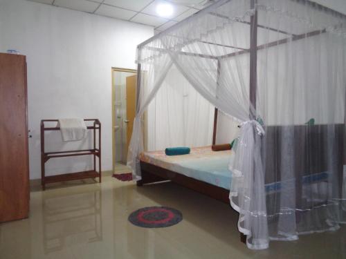 a bedroom with a bed with a mosquito net at Green Valley Home stay in Talpe