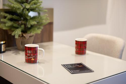two coffee cups on a table with a christmas tree at RIVA sleep & chill in Valjevo