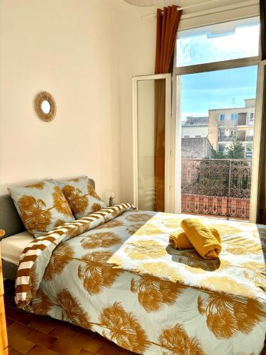 une chambre avec un lit avec une grande fenêtre dans l'établissement Appartement cosy au cœur de Sète, à Sète