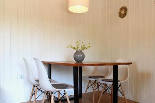 une table avec des chaises blanches et un vase avec des fleurs dessus dans l'établissement Ferienhaus am Reiterhof, à Wernigerode