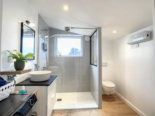 uma casa de banho branca com um lavatório e um WC em La Pommedepin Ravissante maisonnette avec jardin em Plouescat