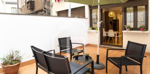 eine Gruppe von Stühlen und ein Sonnenschirm auf einer Terrasse in der Unterkunft Loft Arco de los zapatos,Casco histórico Oviedo in Oviedo