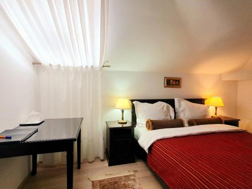 a bedroom with a bed with a desk and a window at Vila Leonida - RESORT LEONIDA in Buşteni
