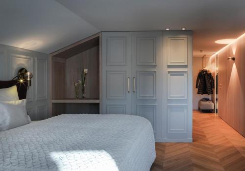 a bedroom with a white bed and a closet at Hotel Zürserhof in Zürs am Arlberg