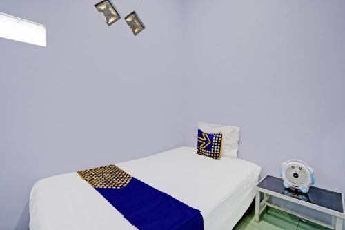 a white bedroom with a bed and a table at OYO Life 92937 Kost Putri Sarkara Syariah in Banyuwangi