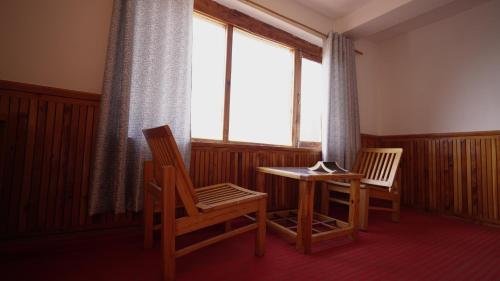 Una habitación con dos sillas y una mesa y una ventana. en BARFI MANALI, en Manali