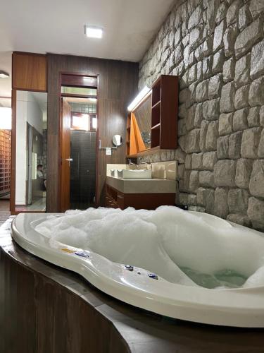 a large bath tub in a bathroom with a stone wall at Espaço Casa in Campina Grande