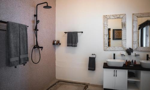 ein Bad mit einer Dusche, 2 Waschbecken und einem Spiegel in der Unterkunft Kolokolo Safari Home in Lentswelemoriti