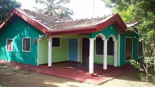 una pequeña casa verde con techo rojo en Thurusewana guest, en Anuradhapura
