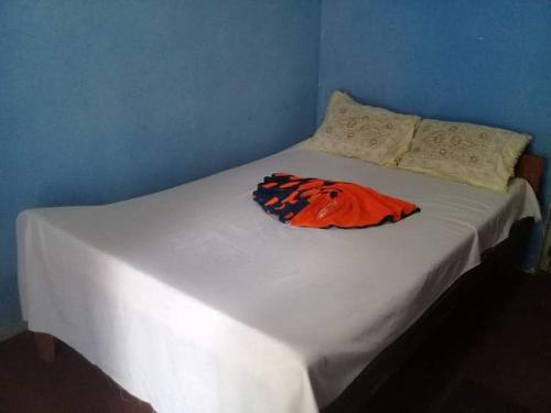 Una cama blanca con una camisa naranja. en Thurusewana guest, en Anuradhapura
