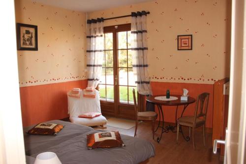 a bedroom with a bed and a table and a window at Le Grenier d'Emma 
