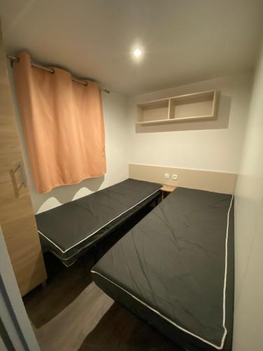 Habitación pequeña con cama y cortina en Mobilhome en Vias