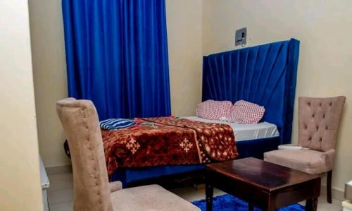 a bedroom with a bed with blue curtains and a table at Ziggon villa mtwapa in Mombasa