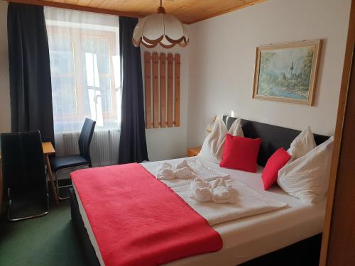 a bedroom with a large bed with red and white pillows at Weisses Rössel-Cavallo Bianco in Werfen