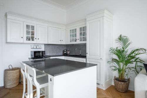 une cuisine avec des armoires blanches et un comptoir noir dans l'établissement MAJESTIC - Somptueux studio en plein coeur de Menton, à Menton