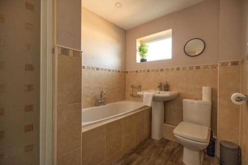 a bathroom with a tub and a toilet and a sink at Pine House By Horizon Stays in Hartlepool