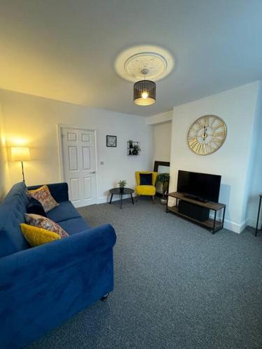 a living room with a blue couch and a clock at Cosy home in Barnsley centre in Barnsley