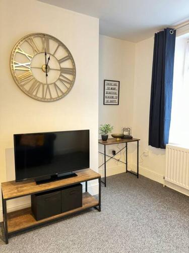 a living room with a tv and a large clock on the wall at Cosy home in Barnsley centre in Barnsley