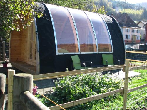 a greenhouse in a garden with chairs in it at Le Repaire de Mitzerlé in Mitzach