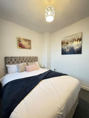 a bedroom with a large bed with two pictures on the wall at Cosy home in Barnsley centre in Barnsley