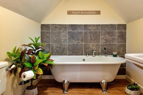 a white bath tub in a bathroom with plants at Finest Retreats - Ty Nant in Aberhafesp