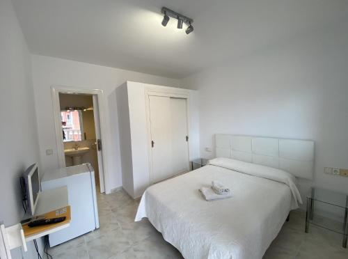 a white bedroom with a bed and a tv at Hotel Las Camelias in Sotogrande