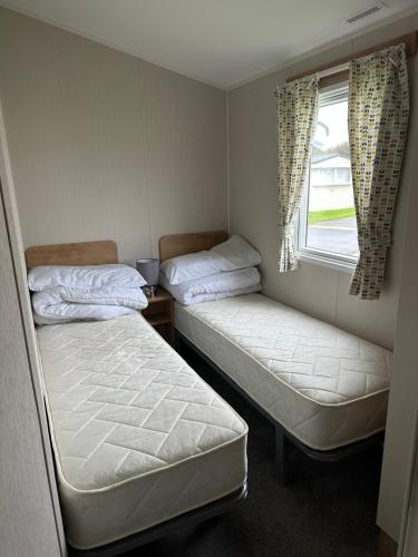 two beds in a small room with a window at Powys 37 in Borth