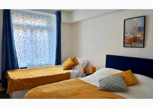 dwa łóżka w pokoju z oknem w obiekcie Clifton’s Cosy Escape w Bristolu
