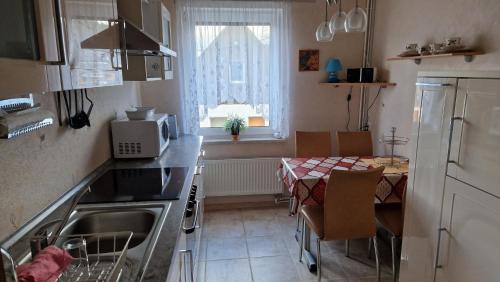 cocina con fregadero, mesa y ventana en Ferienhaus LIANE 