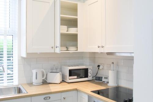 a kitchen with white cabinets and a microwave at Cosy house in West Yorkshire in Batley