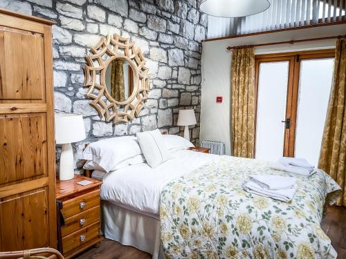 um quarto com uma cama e uma parede de pedra em The Old Mill Holiday Cottages, Nr Mold em Mold