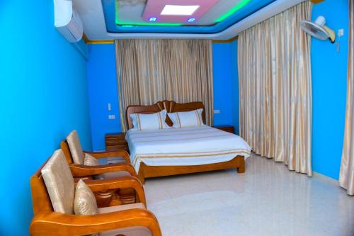 a bedroom with a bed and two chairs and a tv at lake palace beach hotel in Bujumbura