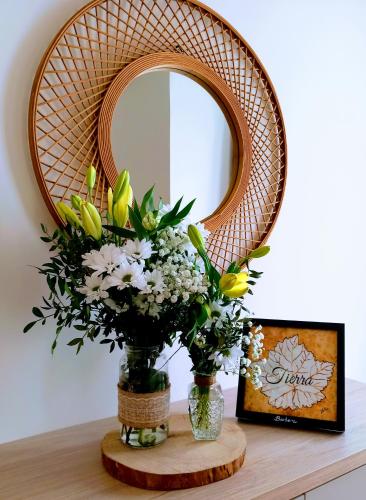 a mirror and a vase with flowers on a table at Casa de las Lías in Chinchón